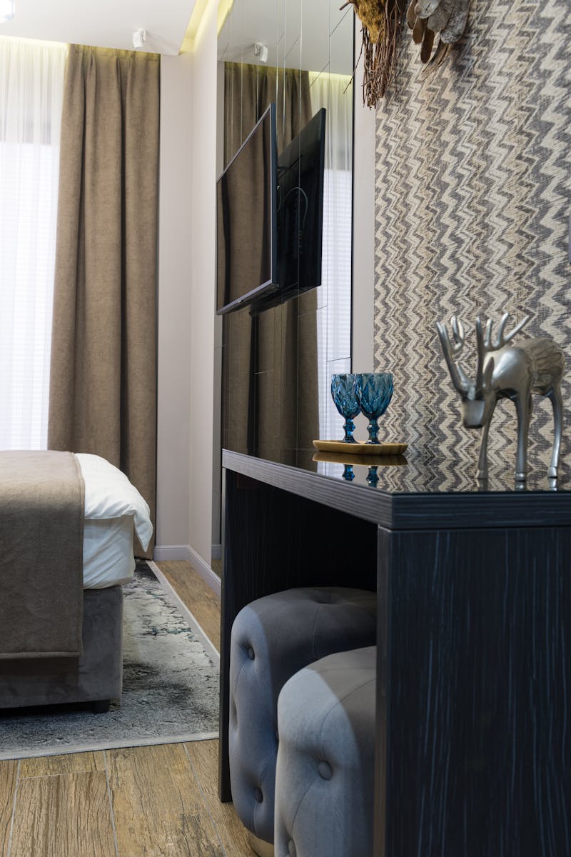 Contemporary bedroom interior with elegant decor, including a statuette and mounted TV, offering a cozy atmosphere.